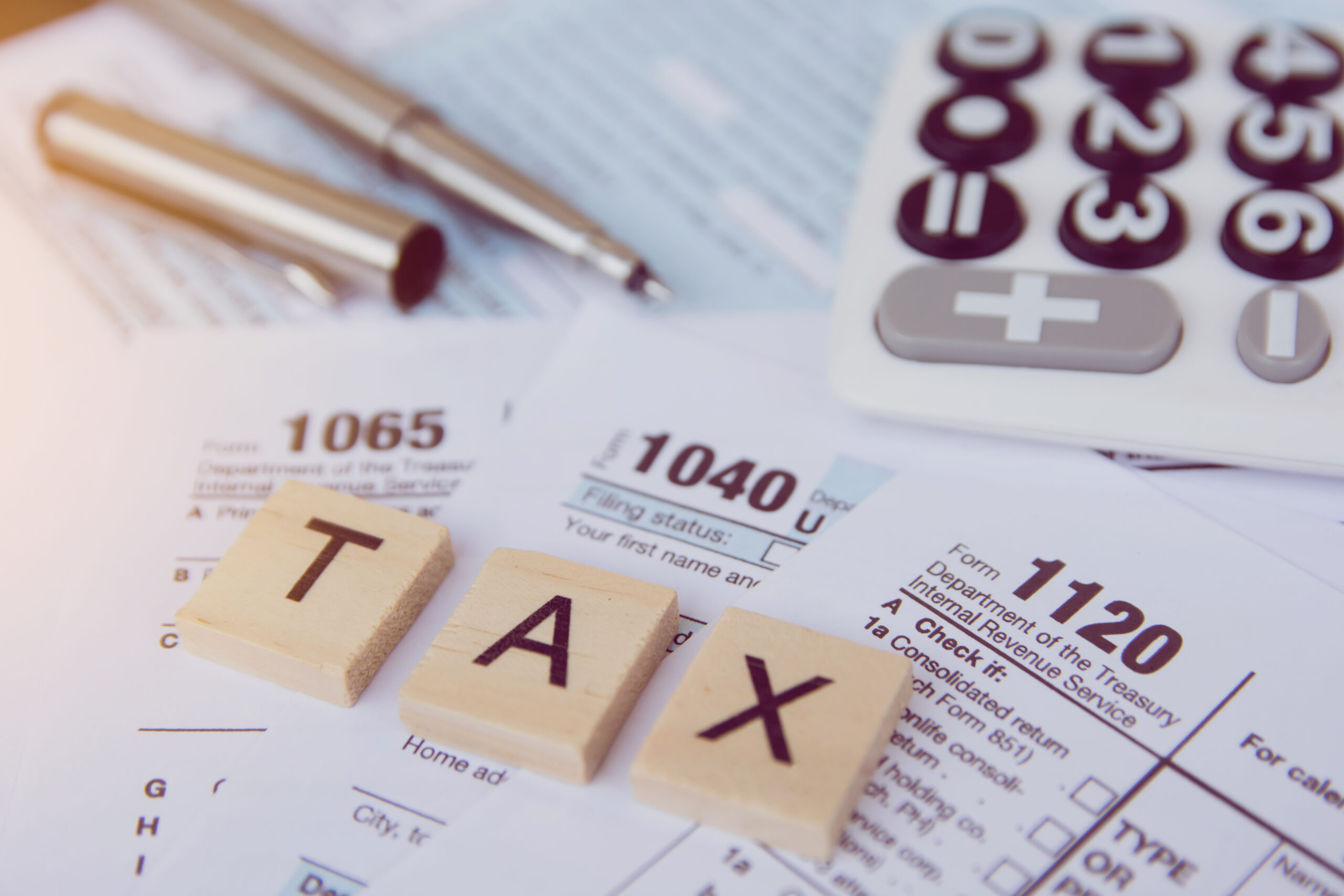 Tax season with wooden alphabet blocks, calculator, pen on 1040