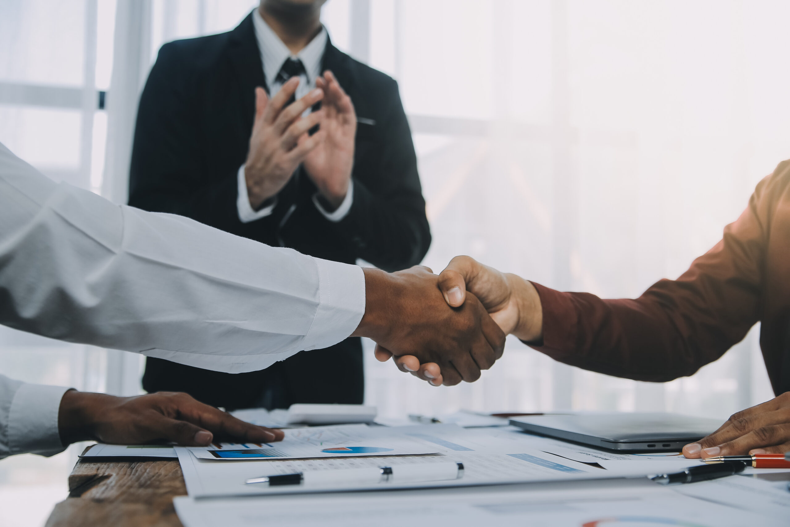 Real estate agent and customers shaking hands together celebrating finished contract after about home insurance and investment loan, handshake and successful deal.
