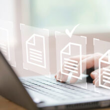 Hand using laptop computer with virtual screen and document for online approve paperless quality assurance and ERP management concept.